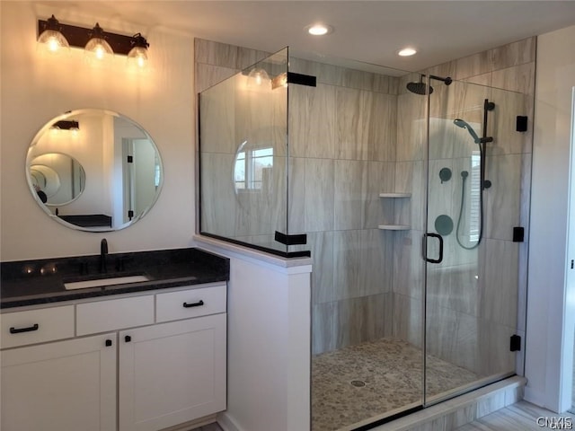 bathroom featuring a shower with door and vanity