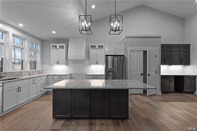 kitchen featuring hardwood / wood-style floors, light stone countertops, stainless steel fridge with ice dispenser, and white cabinets