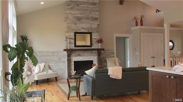 living room featuring a fireplace, high vaulted ceiling, and light hardwood / wood-style floors