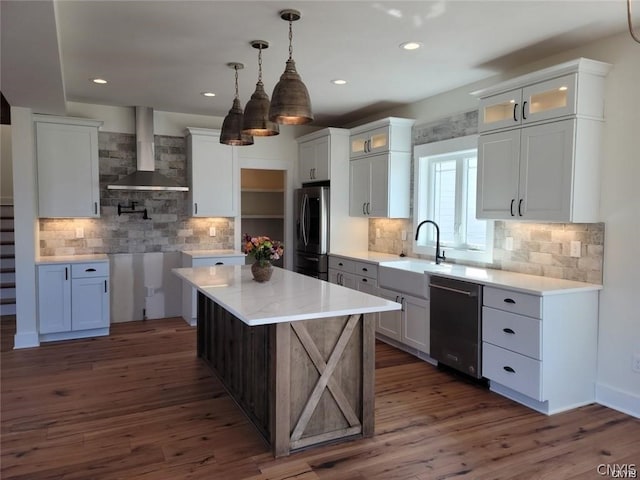 kitchen with stainless steel appliances, decorative backsplash, dark wood-type flooring, white cabinets, and wall chimney range hood