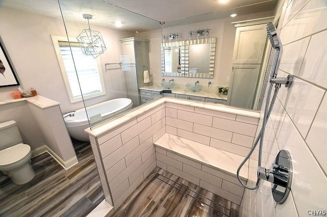 bathroom featuring toilet, hardwood / wood-style flooring, a chandelier, and tiled bath