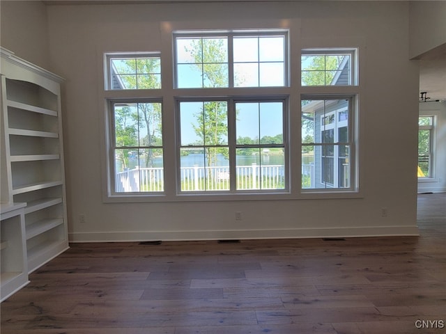 unfurnished living room with dark hardwood / wood-style flooring and a water view