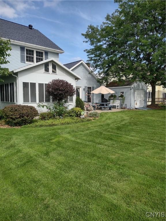 back of house featuring an outbuilding and a lawn