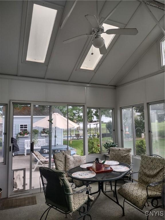 sunroom / solarium with ceiling fan, vaulted ceiling, and a wealth of natural light