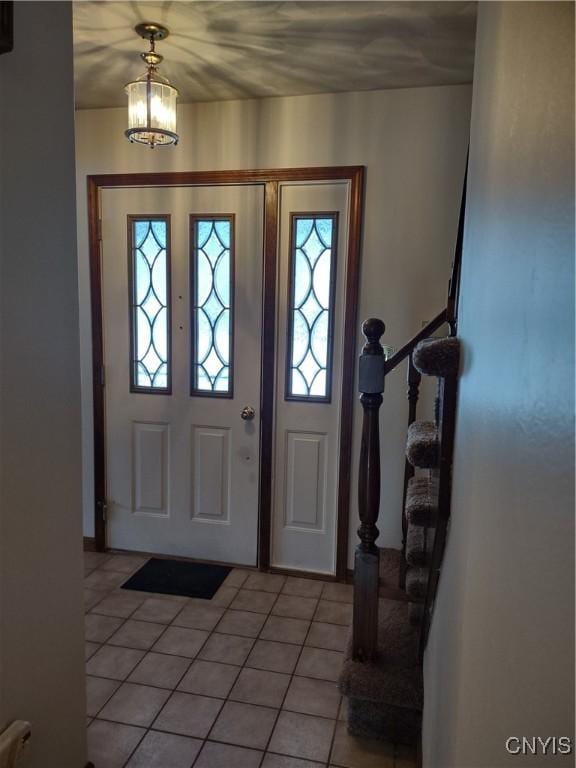 tiled entrance foyer with a chandelier