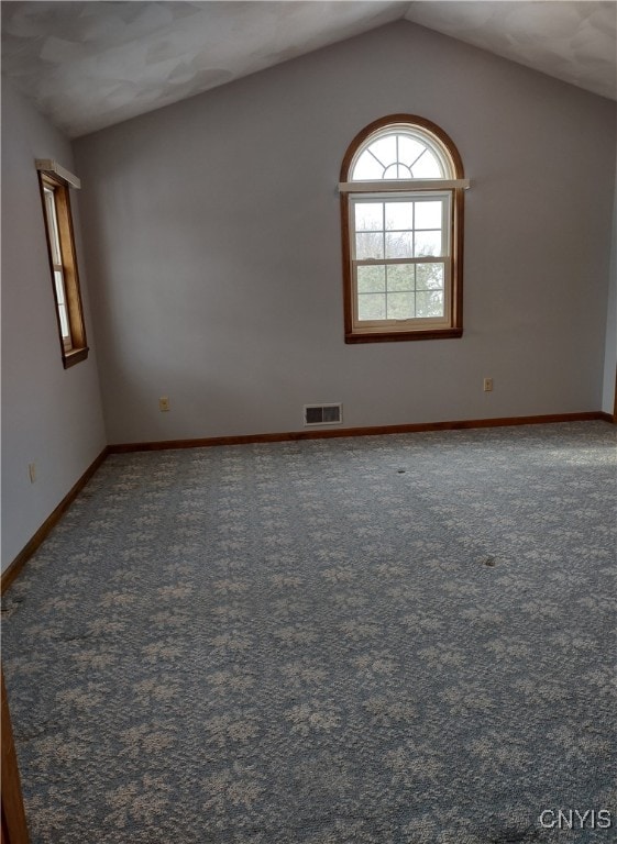 carpeted spare room with lofted ceiling