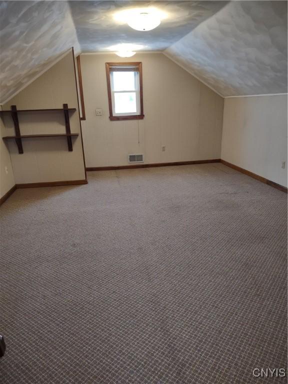 additional living space with vaulted ceiling and light carpet