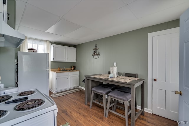 kitchen with a paneled ceiling, range, white cabinets, white fridge, and hardwood / wood-style flooring