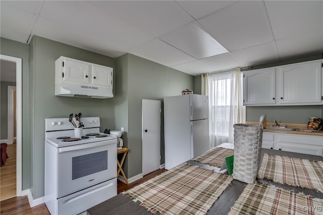 kitchen with white cabinets, a drop ceiling, white appliances, and wood-type flooring