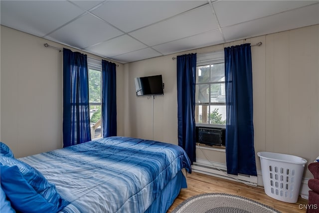 bedroom with multiple windows, light hardwood / wood-style flooring, and a paneled ceiling