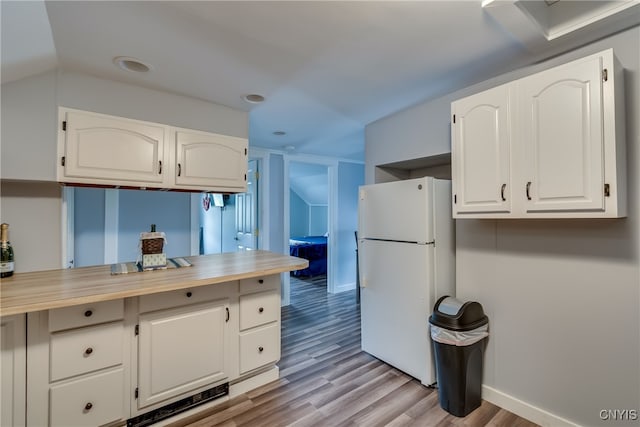 kitchen featuring light wood-type flooring, vaulted ceiling, white refrigerator, and white cabinets