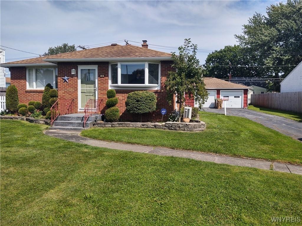 view of front of house featuring brick siding, a front lawn, and a detached garage