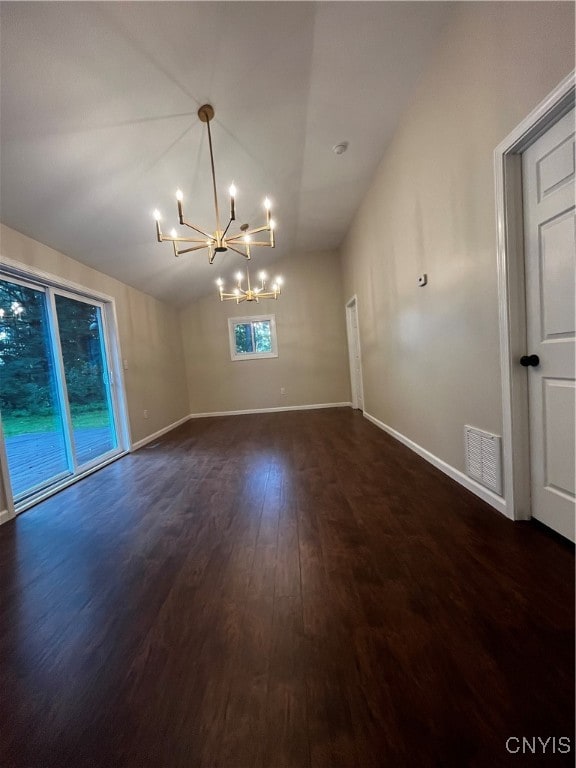 unfurnished room with plenty of natural light, dark hardwood / wood-style flooring, a chandelier, and vaulted ceiling