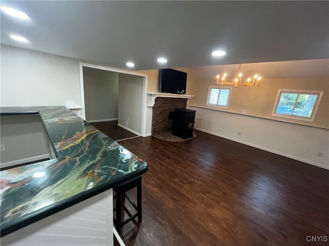 living room with dark wood-type flooring, a chandelier, and a fireplace