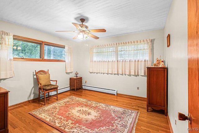 living area with ceiling fan, baseboard heating, and light hardwood / wood-style flooring