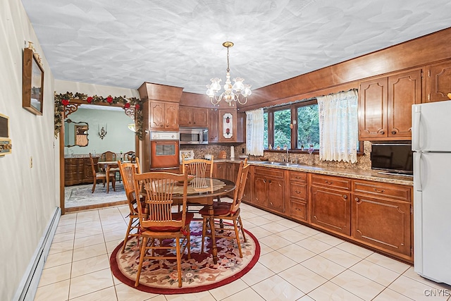 dining space featuring sink, baseboard heating, a notable chandelier, a textured ceiling, and light tile patterned flooring