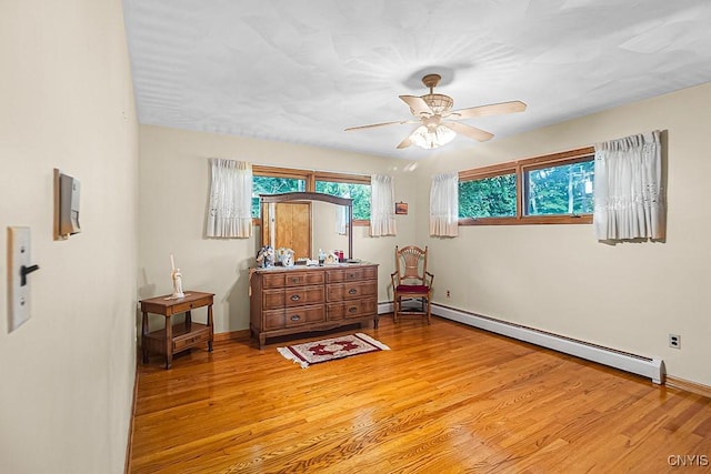 interior space featuring ceiling fan, light hardwood / wood-style flooring, and a baseboard heating unit