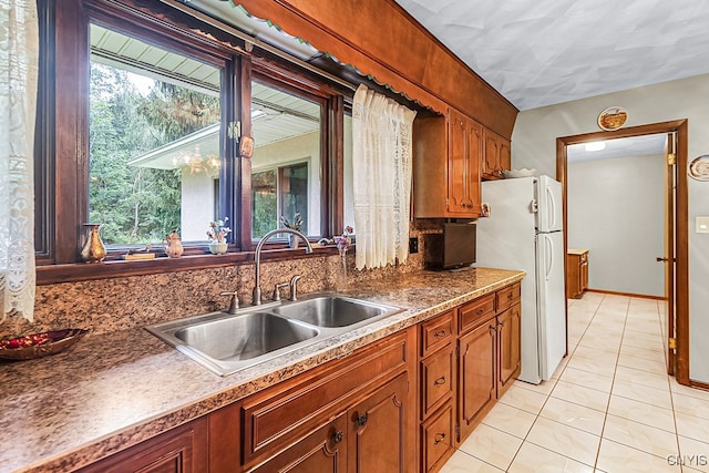 kitchen with sink, light tile patterned floors, and white refrigerator