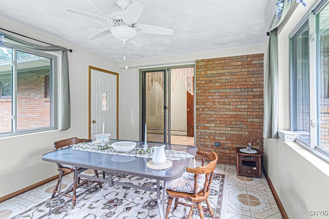 dining area featuring ceiling fan and brick wall