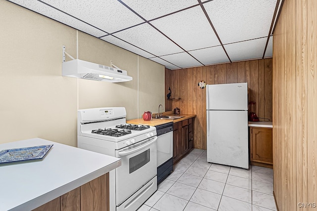 kitchen featuring wood walls, sink, a drop ceiling, and white appliances