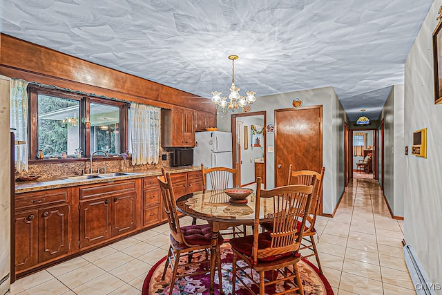 tiled dining space with baseboard heating, sink, a textured ceiling, and a notable chandelier