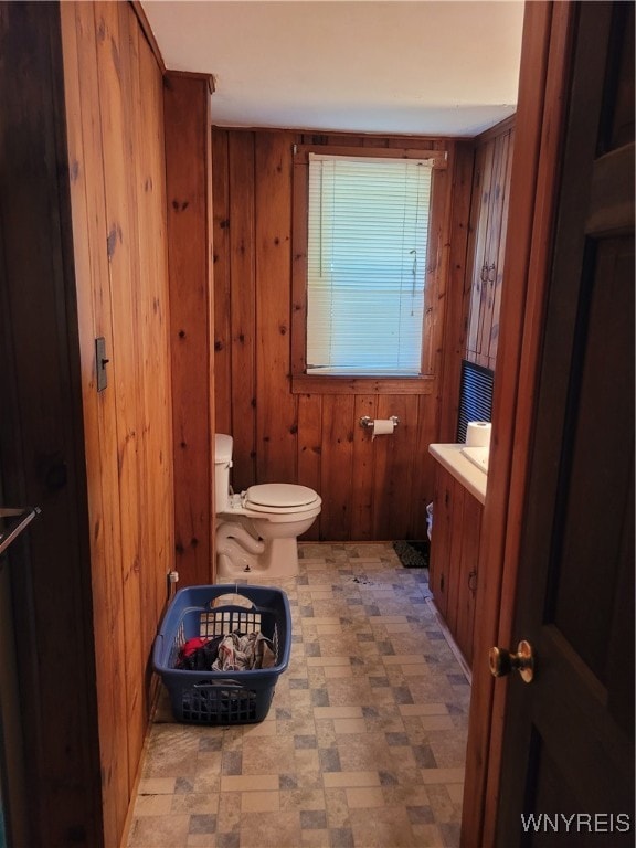 bathroom featuring wooden walls, vanity, and toilet