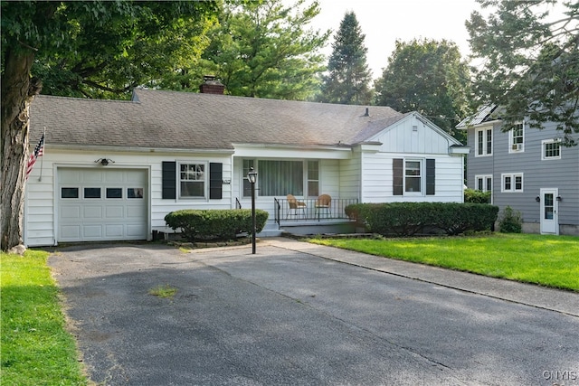 ranch-style home featuring a porch, a front yard, and a garage