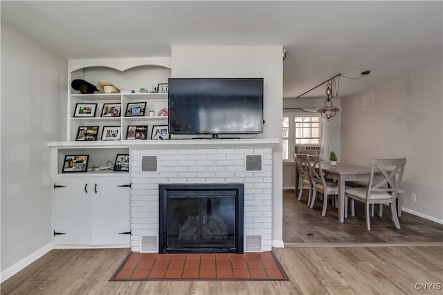 living room featuring hardwood / wood-style flooring and a brick fireplace