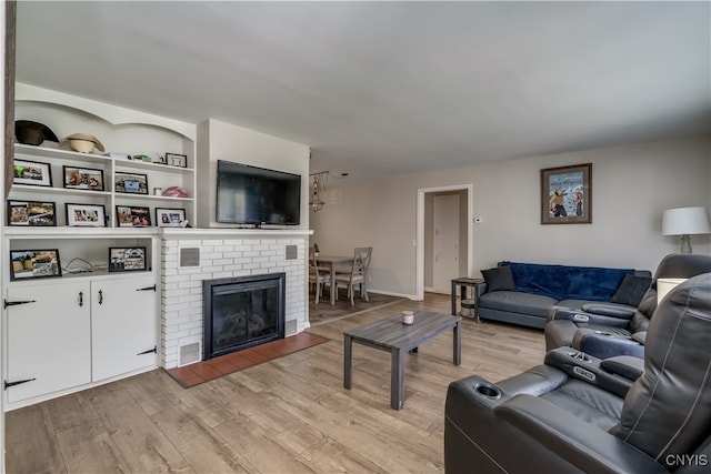 living room with a fireplace, light wood-type flooring, and built in shelves