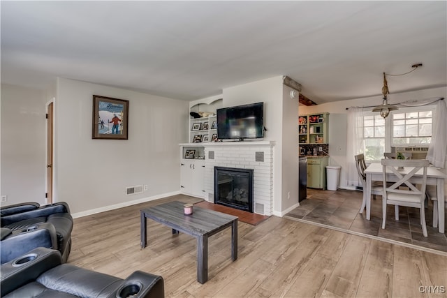 living room with wood-type flooring and a brick fireplace