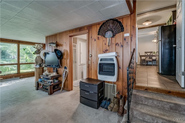 interior space featuring wood walls, carpet, and black fridge