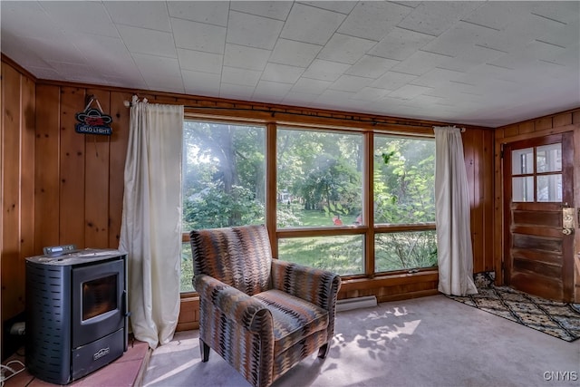 sitting room with light carpet, wooden walls, and a wood stove