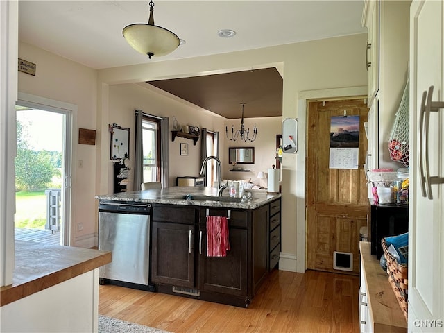 kitchen featuring stainless steel dishwasher, dark brown cabinetry, sink, light wood-type flooring, and dark stone counters