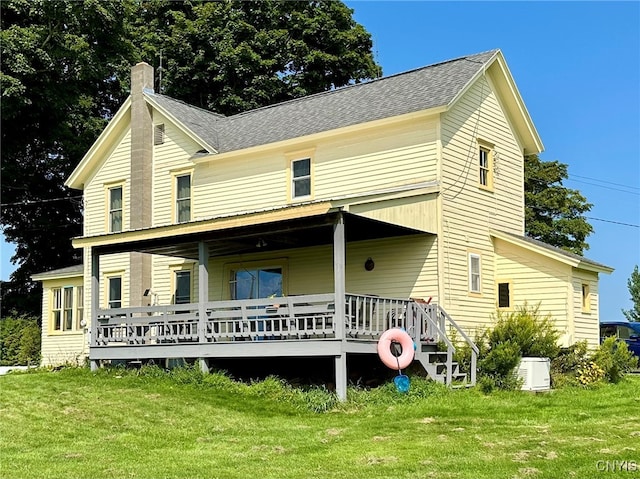 rear view of property featuring a lawn and cooling unit