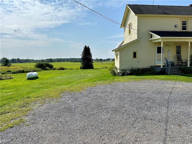 view of side of home with a rural view and a yard