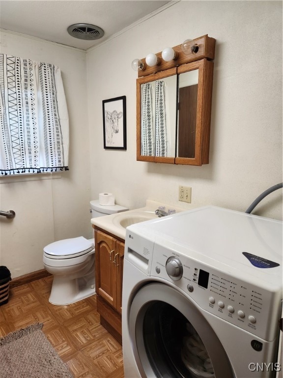 clothes washing area with sink, washer / dryer, and light parquet floors