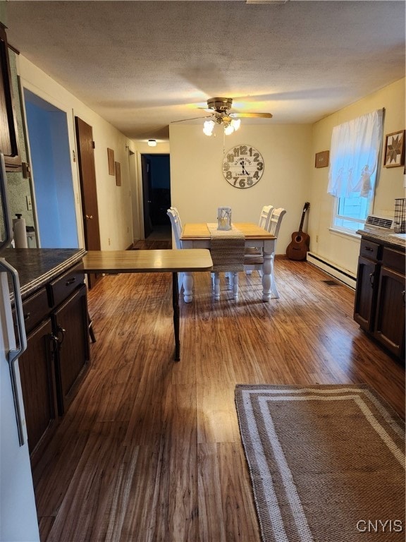 dining room with ceiling fan, a textured ceiling, baseboard heating, and hardwood / wood-style floors