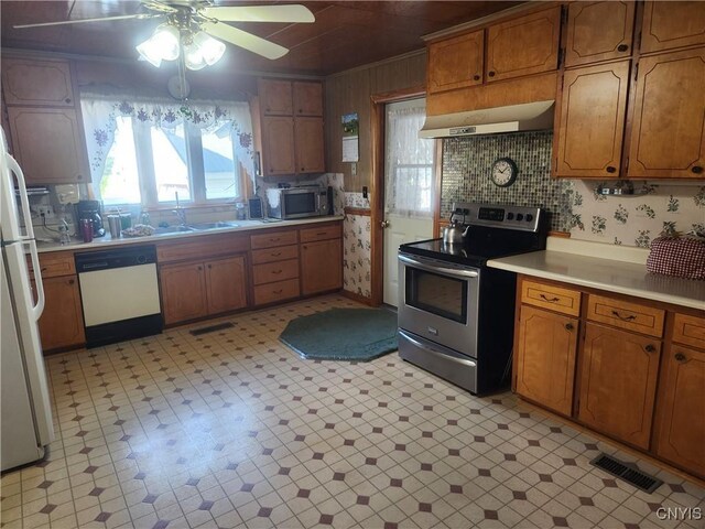 kitchen with under cabinet range hood, visible vents, stainless steel appliances, and brown cabinetry