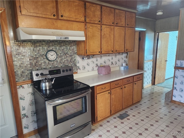 kitchen with wall chimney range hood, light tile patterned floors, electric range, and tasteful backsplash