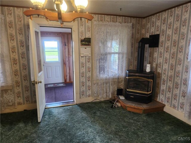 interior space featuring wallpapered walls, an inviting chandelier, a wood stove, and carpet