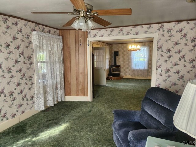 carpeted living area with wallpapered walls, a wood stove, and ornamental molding