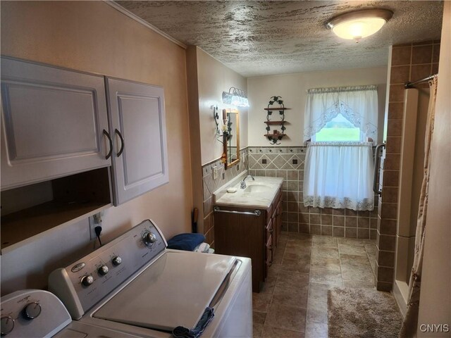 bathroom featuring a shower with shower curtain, a wainscoted wall, separate washer and dryer, a textured ceiling, and tile walls