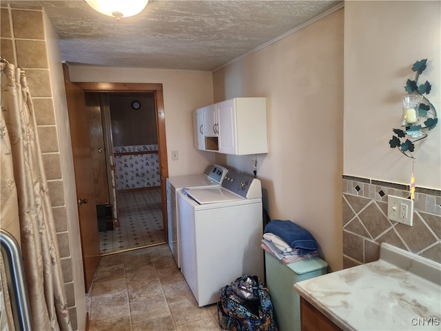 washroom featuring a textured ceiling, washer and clothes dryer, light tile patterned flooring, and cabinets