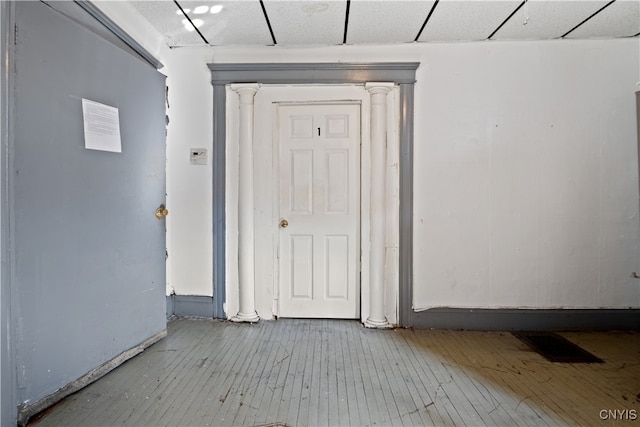 interior space with a drop ceiling and hardwood / wood-style flooring