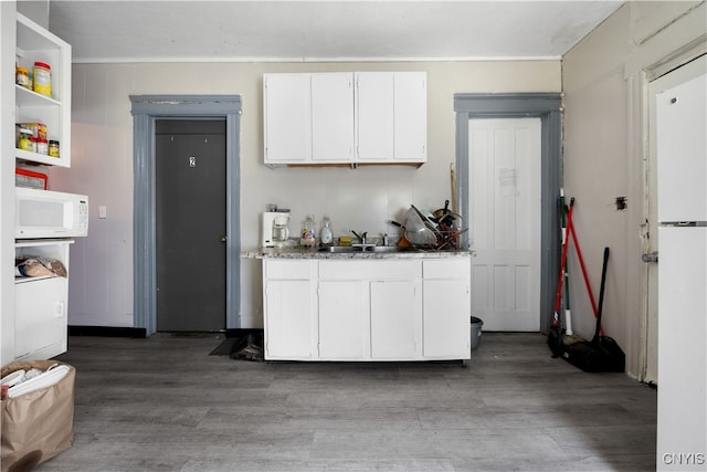 kitchen with hardwood / wood-style flooring, white cabinets, sink, and dark stone counters