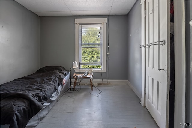 bedroom featuring multiple windows, hardwood / wood-style floors, and a drop ceiling