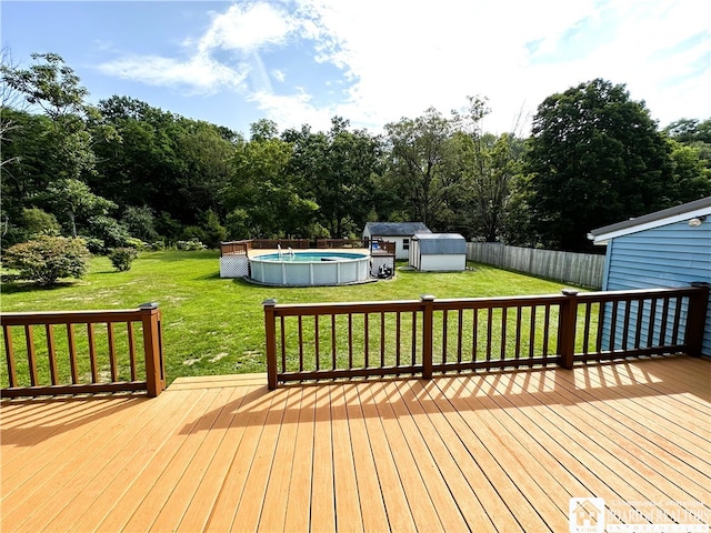 wooden terrace featuring a yard, a storage unit, and a fenced in pool