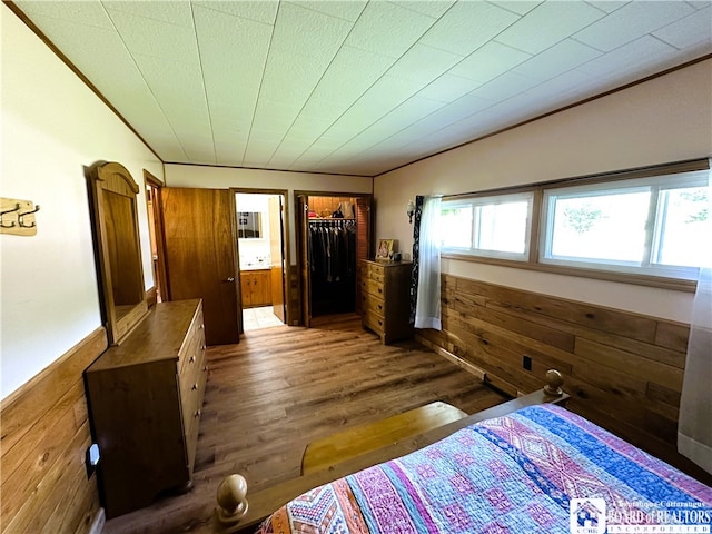 unfurnished bedroom featuring a closet, wood walls, a spacious closet, and dark wood-type flooring