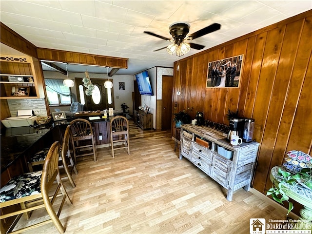 interior space with light hardwood / wood-style flooring, wooden walls, and ceiling fan