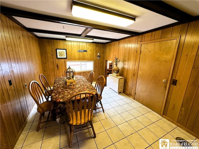 dining room featuring beam ceiling, wooden walls, and light tile patterned floors